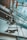 An abstract architectural view of a modern building interior featuring large glass windows and visible metal structures. The perspective gives a dramatic and dynamic upward angle, capturing reflections and intersecting lines between the glass panes and metallic elements.