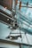 An abstract architectural view of a modern building interior featuring large glass windows and visible metal structures. The perspective gives a dramatic and dynamic upward angle, capturing reflections and intersecting lines between the glass panes and metallic elements.