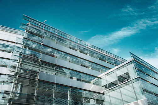 A sleek, glass-fronted building reflecting the sky, showcasing contemporary urban architecture.