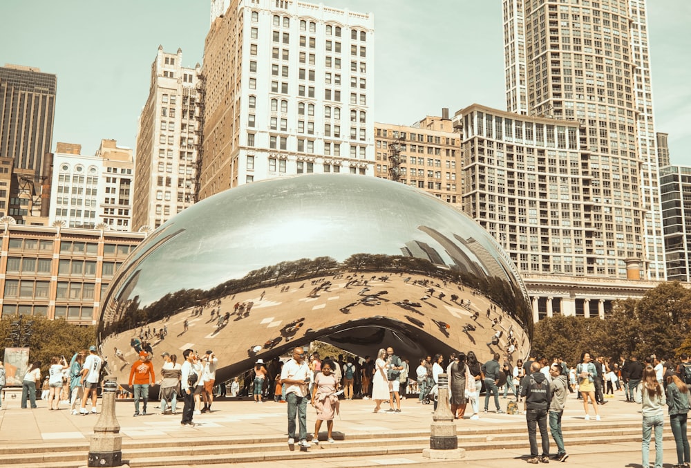 a group of people standing in front of a large metal ball