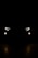 A pair of car headlights and fog lights are illuminated in a dark, night-time setting. The lights are brightly shining against a pitch-black background, giving the impression of a vehicle approaching or standing still in darkness. The headlights have a modern, angular design, and there are two smaller, round fog lights positioned below them.