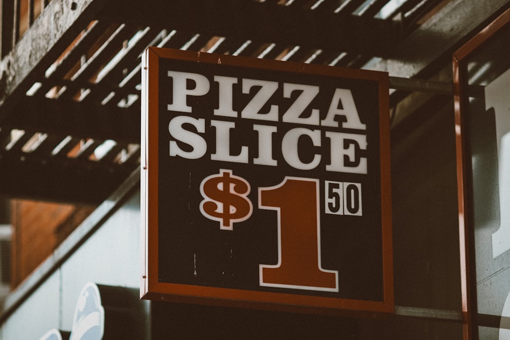 a pizza slice sign hanging from the side of a building