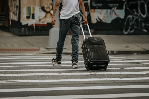 a man walking across a street with a suitcase