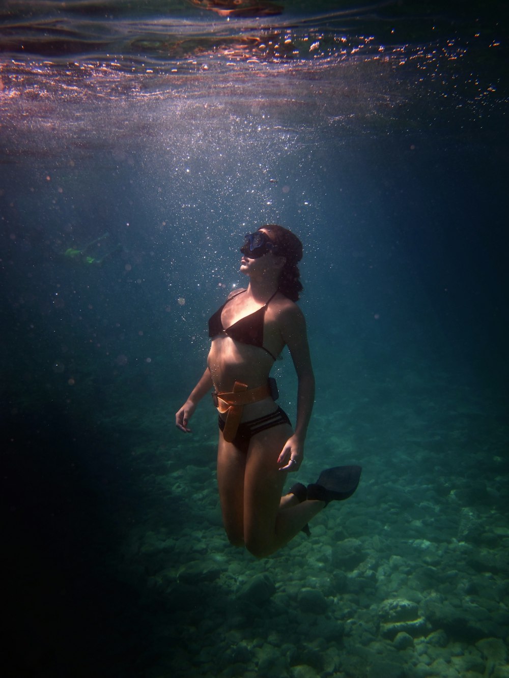 a woman in a bikini swims under the water