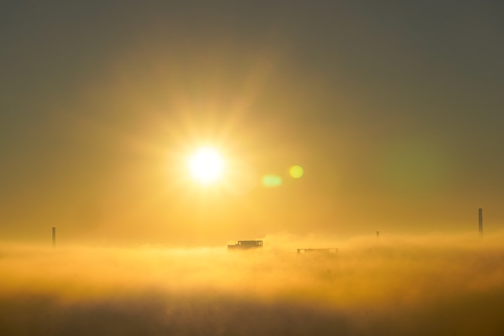 the sun is shining over a foggy field