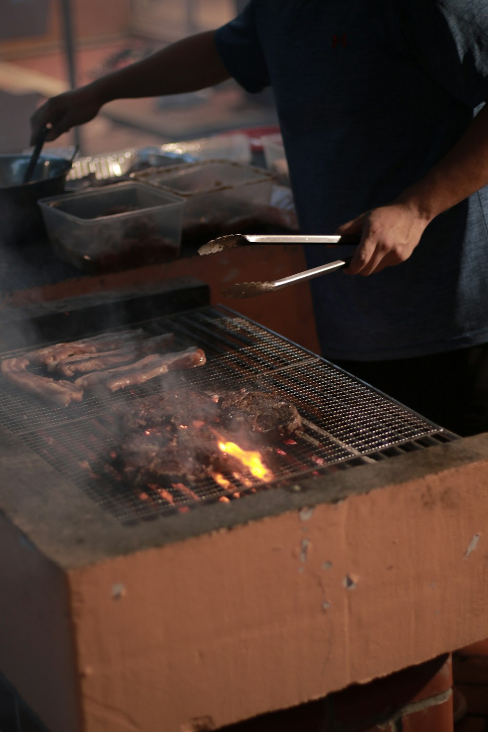 a man cooking food on a grill with tongs