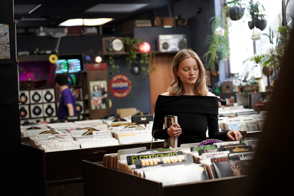 a woman in a black top standing in front of a record store