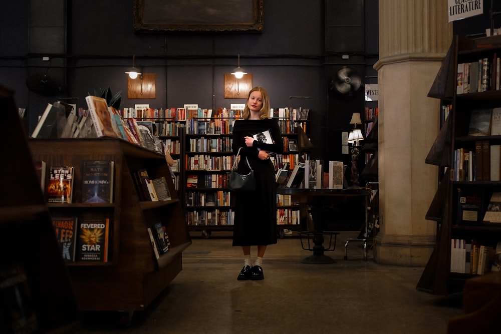 a woman standing in front of a bookshelf filled with books