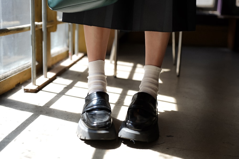 a woman's feet in black shoes and a green purse