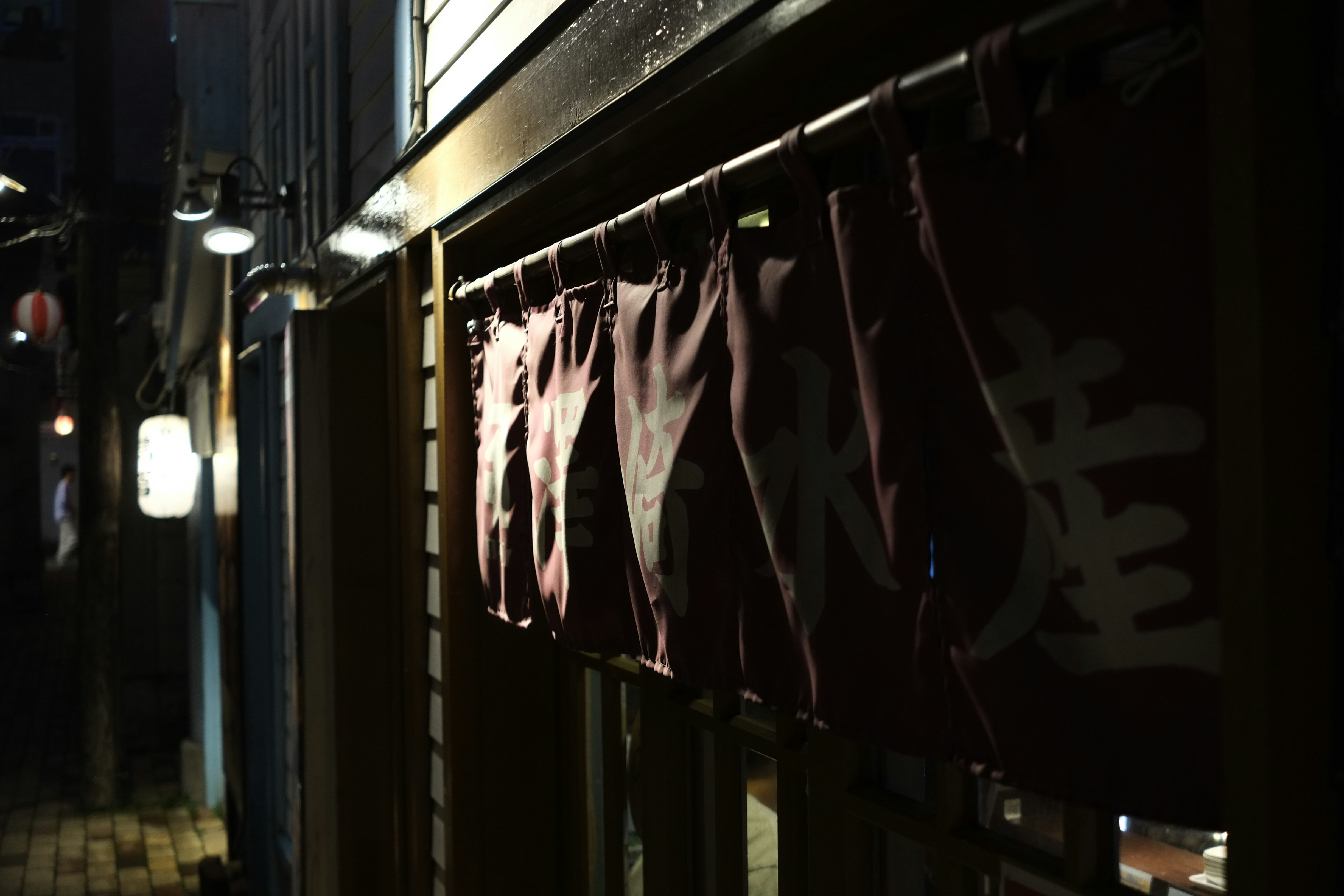 a dark alleyway with a storefront with a sign on it