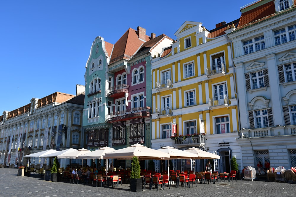 a row of buildings with tables and umbrellas in front of them