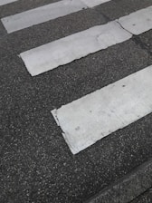 A series of white stripes, possibly a pedestrian crossing, contrasts with the dark, textured pavement. Some of the white paint appears worn or cracked.