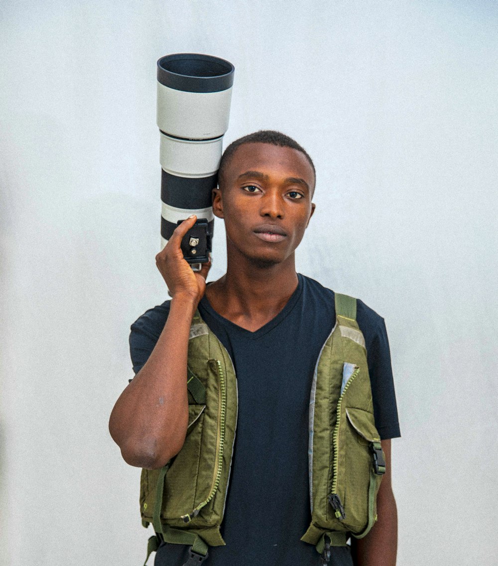a man holding a camera and a large cup