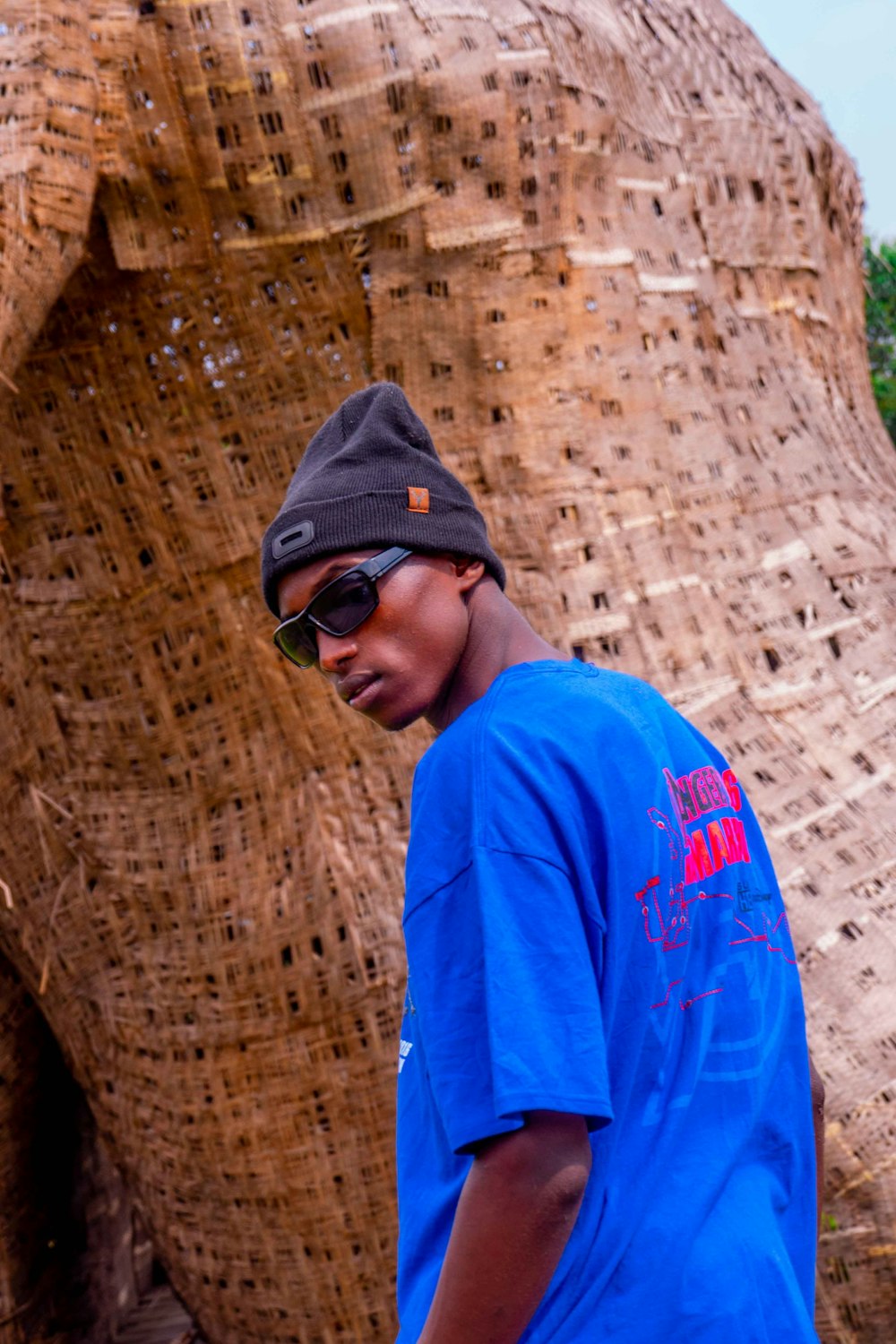 a man in a blue shirt standing next to an elephant