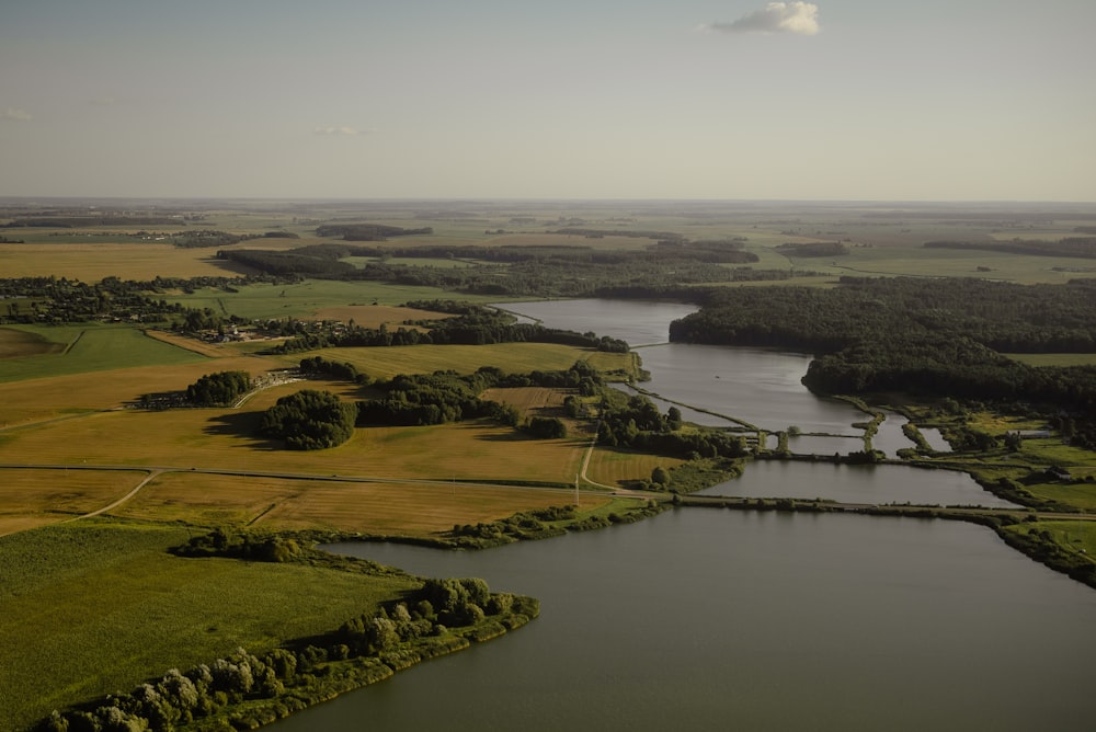 a large body of water surrounded by lush green fields