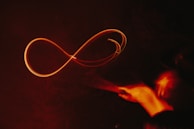 Hands releasing light particles that merge into a digital infinity symbol.