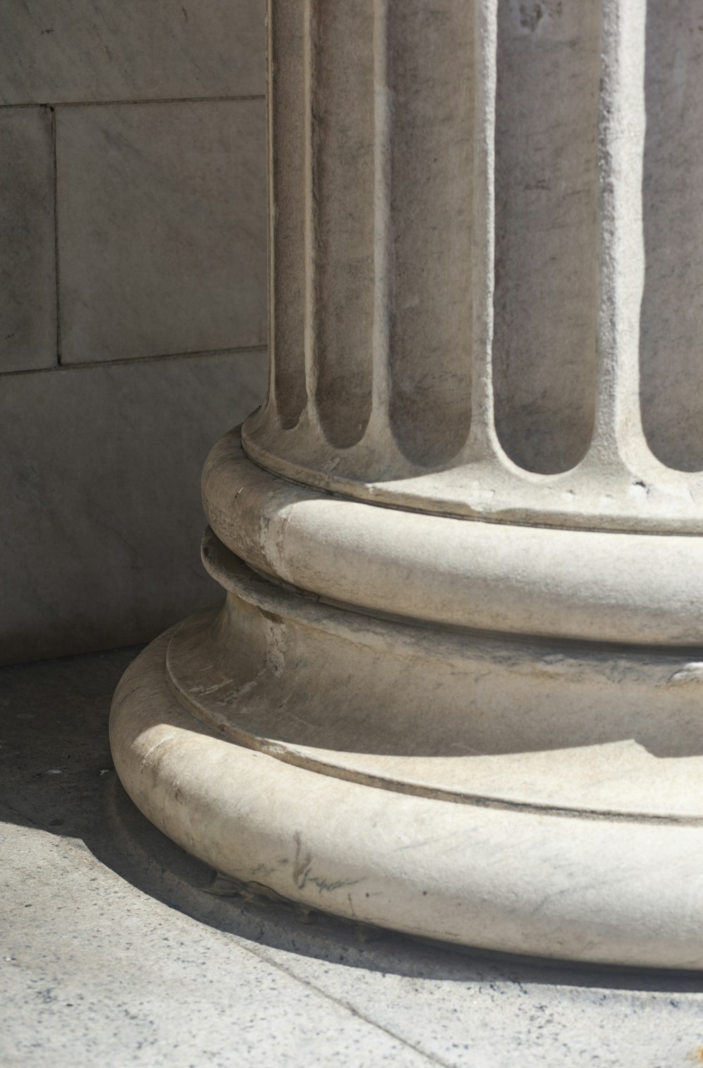 a cat sitting on the ground next to a stone column