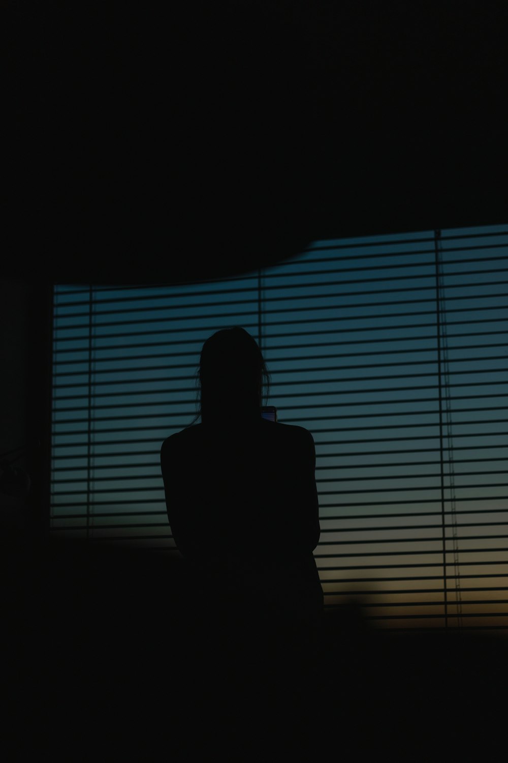 a silhouette of a person sitting in front of a window