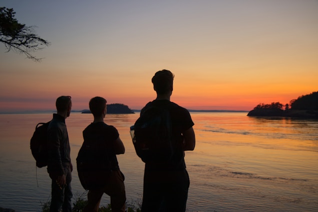 a group of people standing next to a body of water
