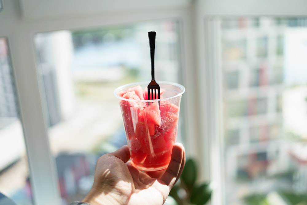 a person holding a plastic cup with a fork in it