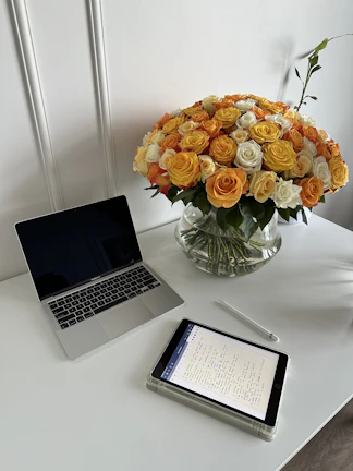 Organized workspace with clean lines, a laptop, and fresh flowers.
