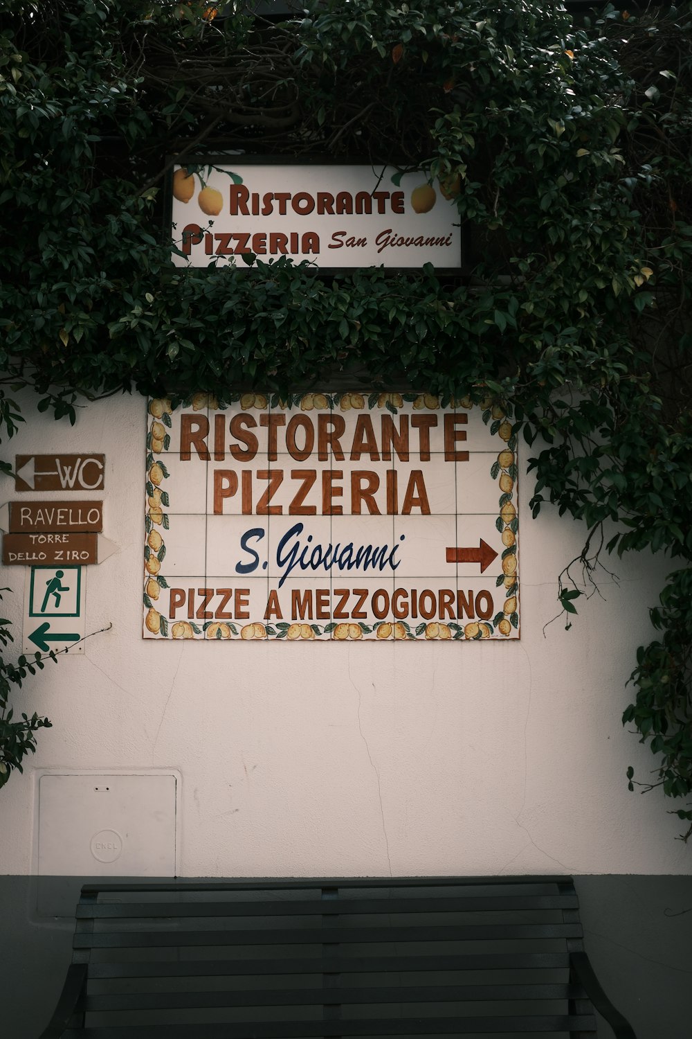 a bench sitting in front of a wall covered in signs