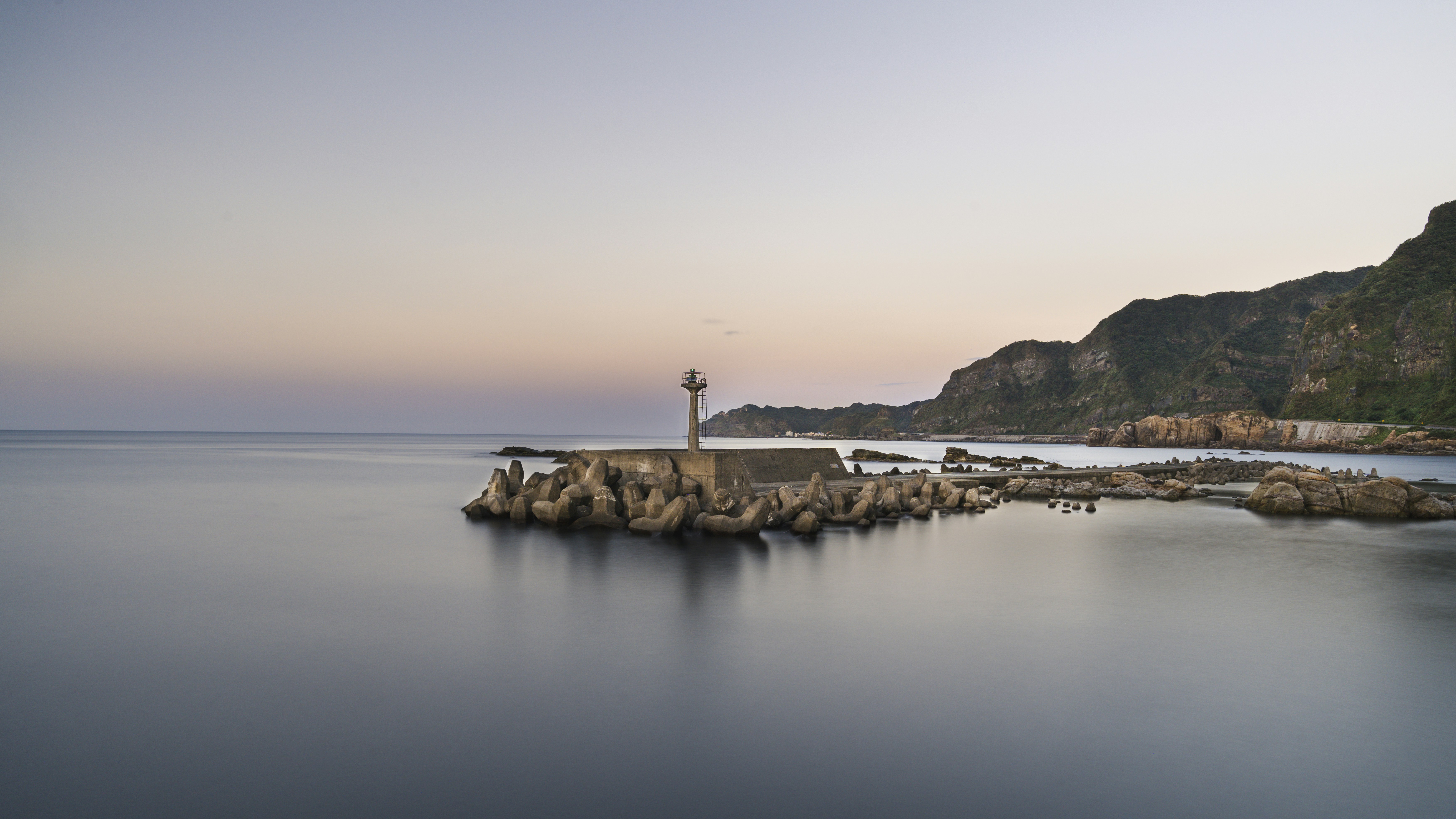 A lighthouse on a rock outcropping in the middle of the ocean photo ...