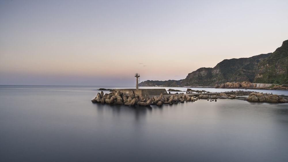 a lighthouse on a rock outcropping in the middle of the ocean