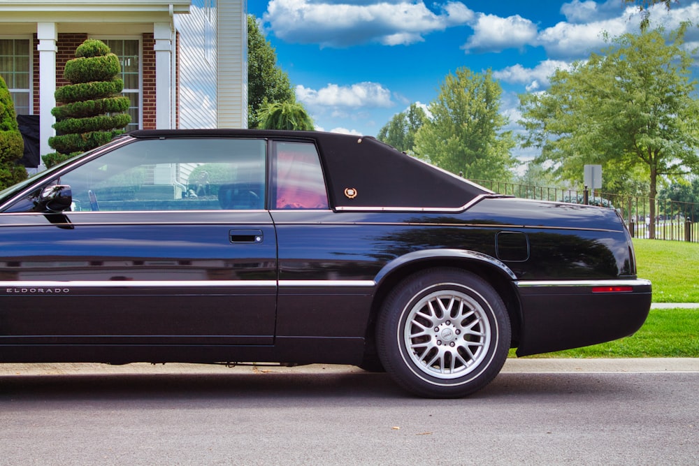 a black sports car parked in front of a house