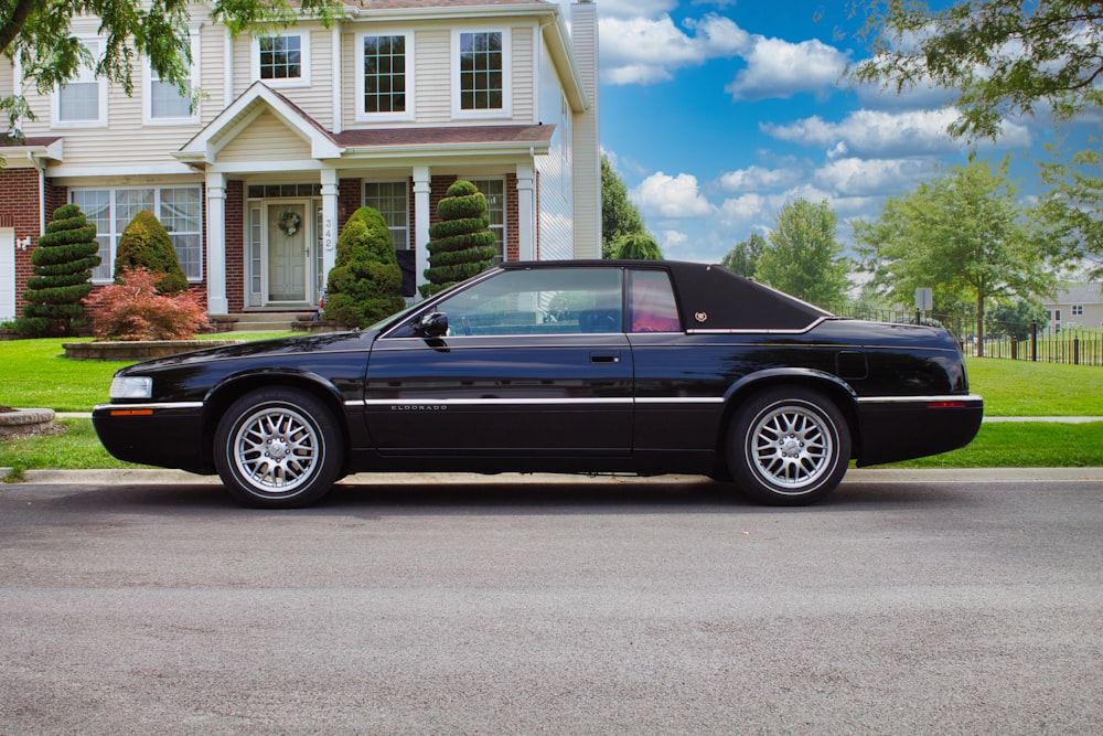 a black sports car parked in front of a house