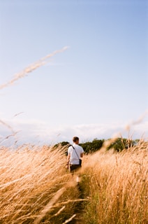 a man walking through a field of tall grass