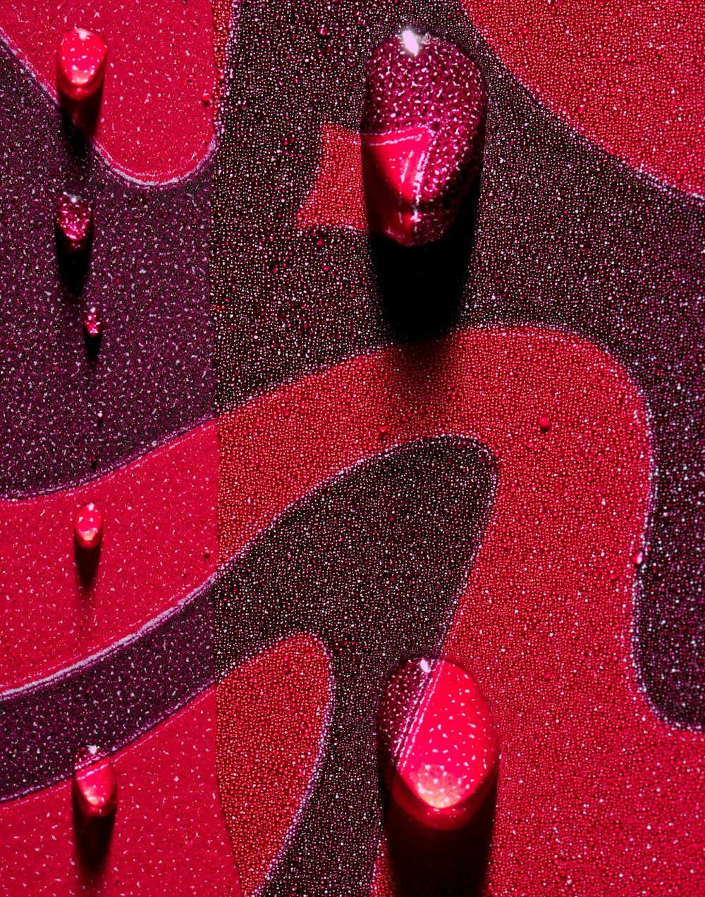 a close up of a red and black surface with drops of water on it