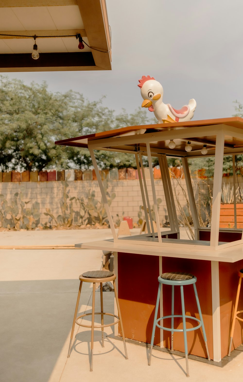 a chicken sitting on top of a bar next to two stools