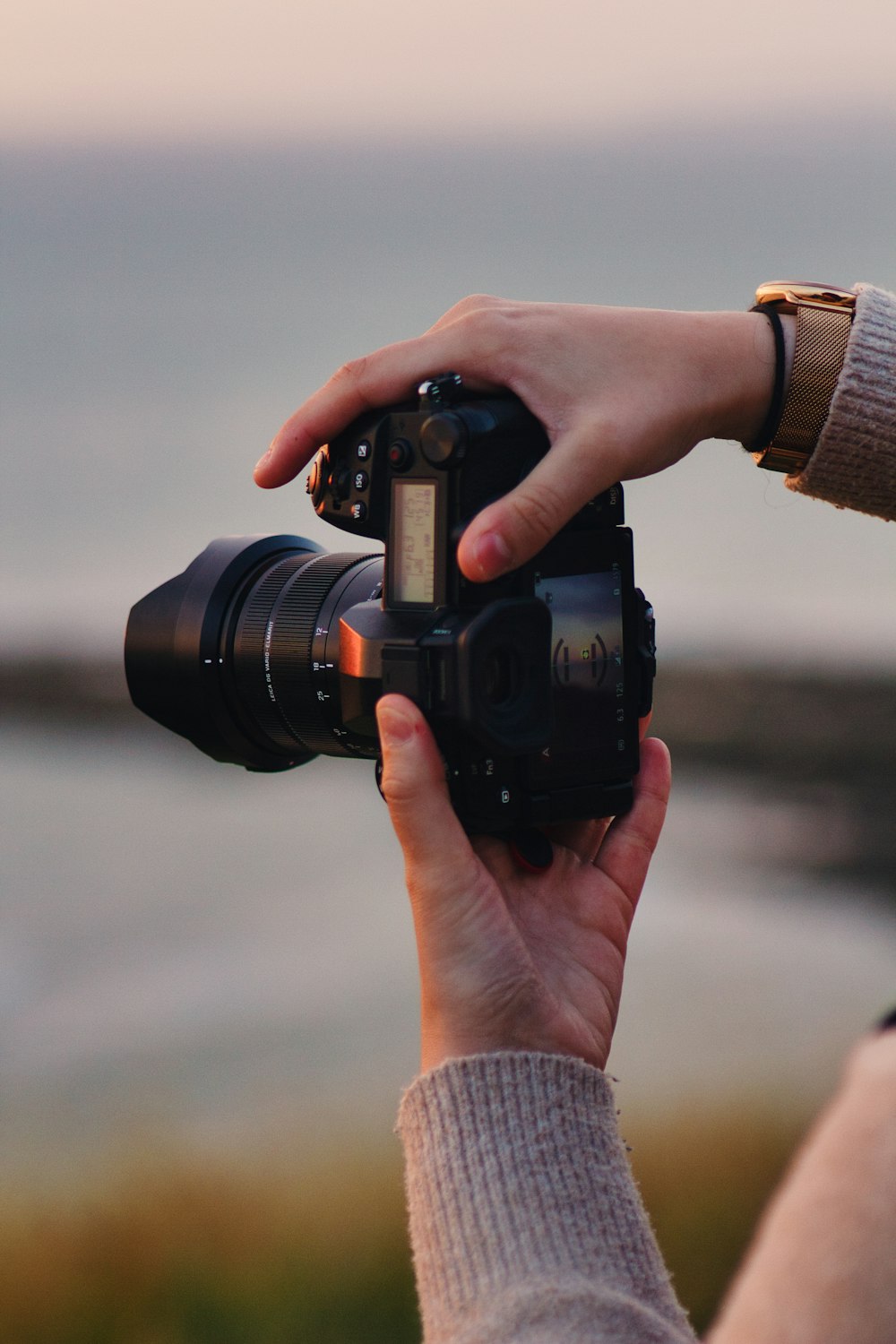 a person holding a camera in front of a body of water