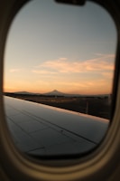 A scenic airplane flying over mountain ranges at sunset