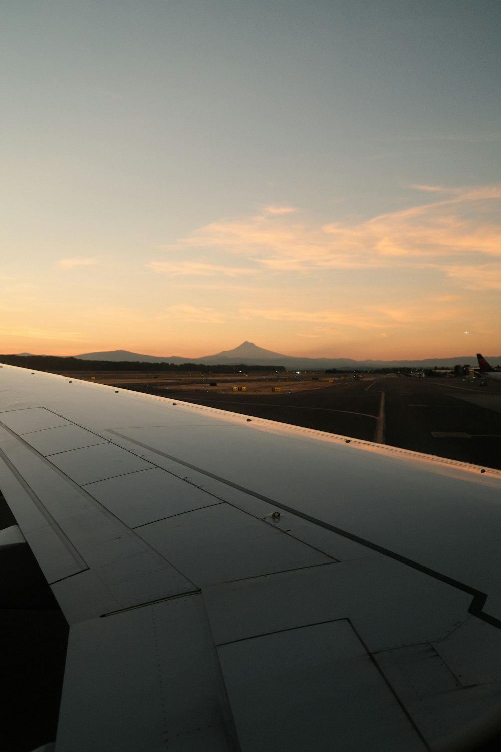 a asa de um avião enquanto o sol se põe