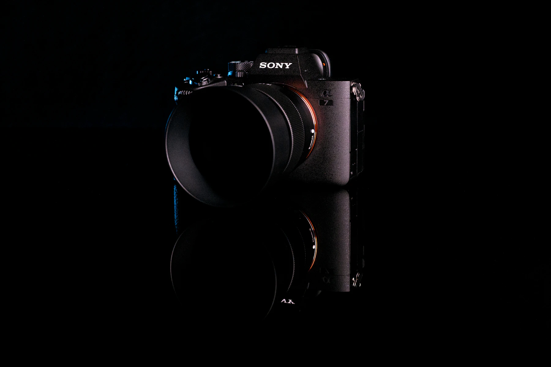A Sony mirrorless camera with a lens, lit from the side on black