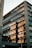 A modern office building with large reflective windows capturing the reflection of another structure. The architecture features sleek lines and a mix of glass and stone materials. The sunlight casts warm tones on the reflected building, enhancing the visual contrast.