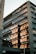A modern office building with large reflective windows capturing the reflection of another structure. The architecture features sleek lines and a mix of glass and stone materials. The sunlight casts warm tones on the reflected building, enhancing the visual contrast.