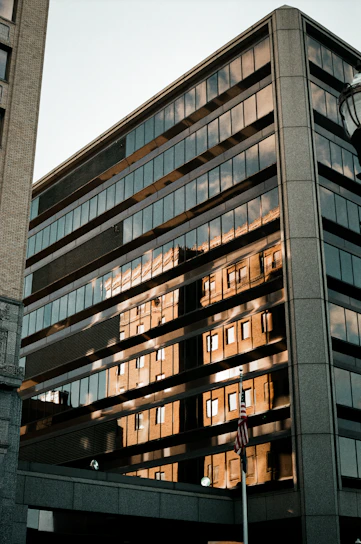 A sleek, modern office building facade in Singapore with warm sunlight reflecting off glass windows.