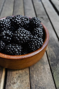 Freshly picked blackberries glistening with morning dew on a rustic wooden table.