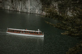 A scenic boat navigating a crystal-clear lake surrounded by lush forests