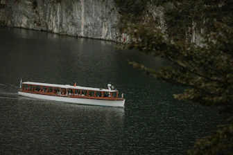 A scenic boat navigating a crystal-clear lake surrounded by lush forests