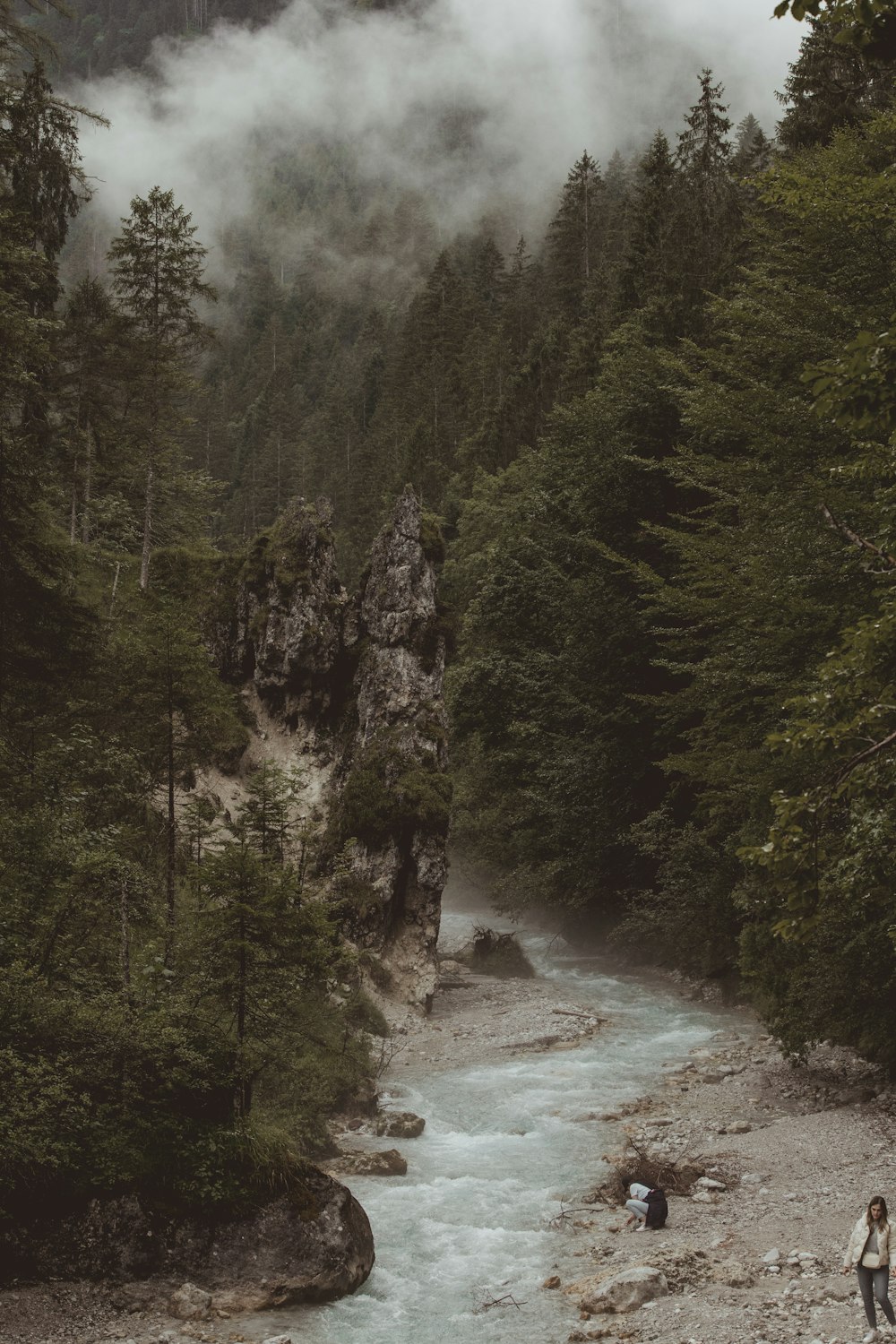 a couple of people standing next to a river