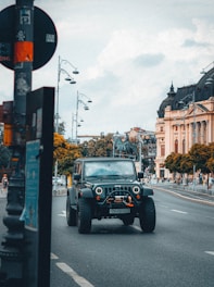 A Jeep Renegade driving through a city street at dusk, with glowing streetlights and a dynamic urban background.