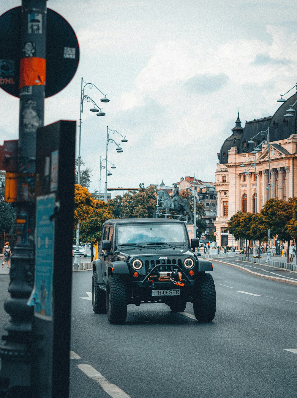 a jeep driving down a street next to a traffic light