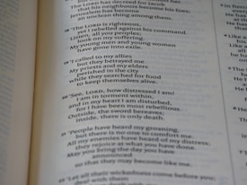 A close-up of a page from an open book, showing printed text in both prose and numbered verses. The text seems to be focused on themes of distress, seeking divine guidance, and historical or religious content.