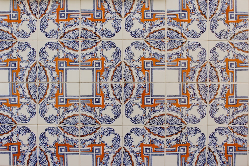 a close up of a tile wall with orange and blue designs
