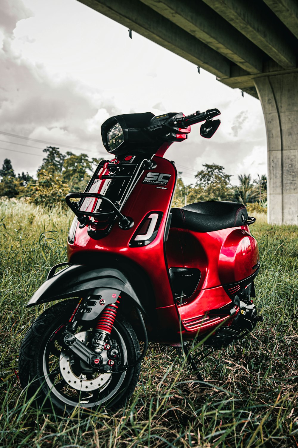 a red scooter is parked under a bridge