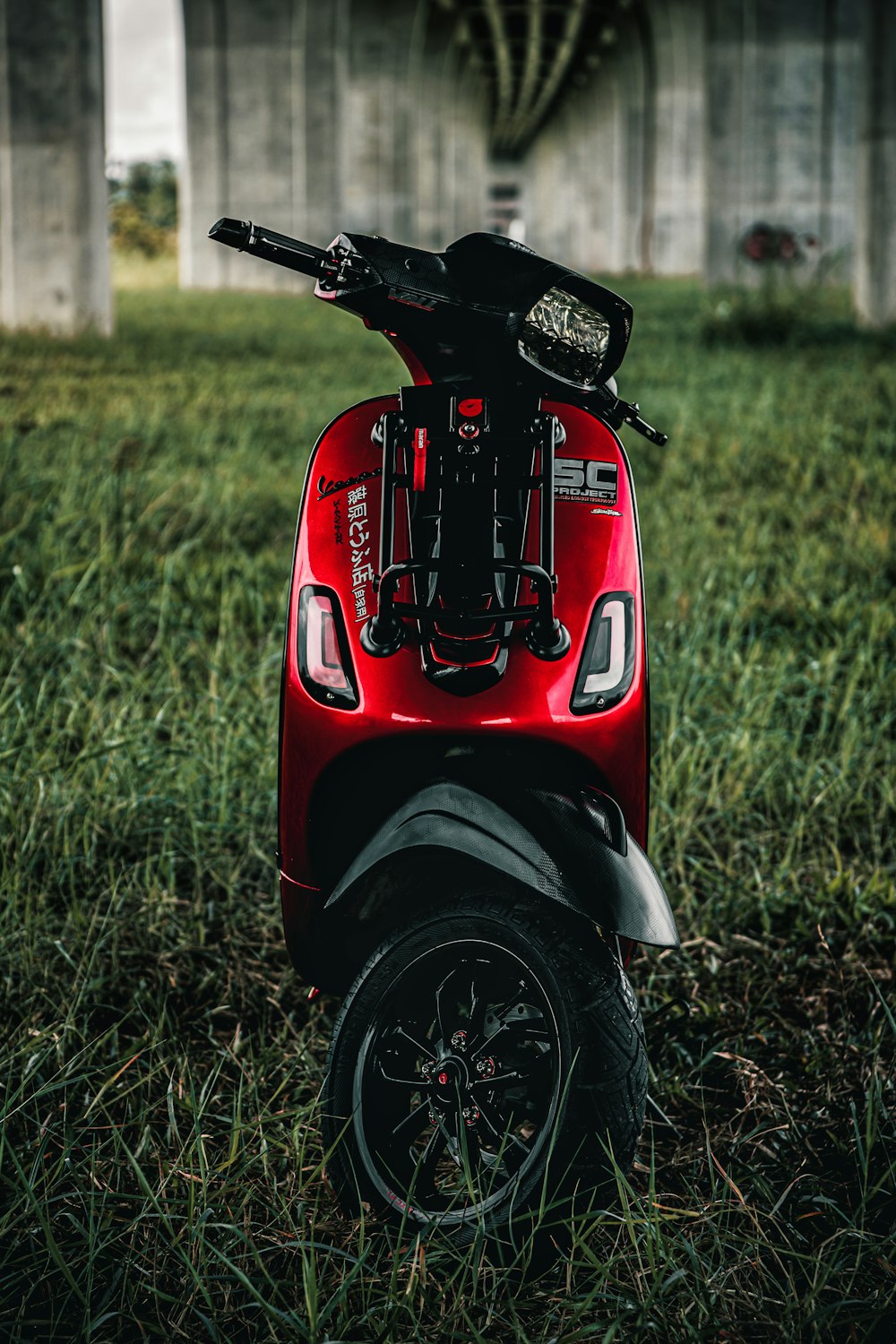 a red scooter parked in a grassy field